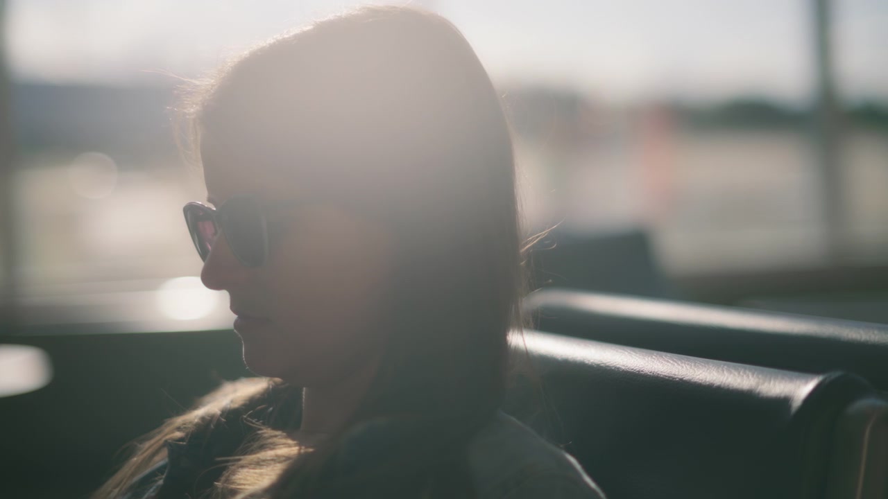 Close up of sun shining upon a woman sitting in the airport terminal