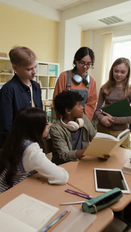 students collaborating and reading a book in a classroom