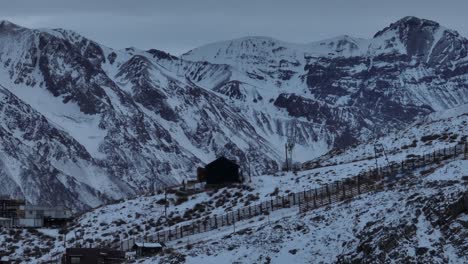 Toma-Aérea-De-Paralaje-De-Casas-En-Farellones-Con-Montañas-Andinas-Nevadas-Detrás