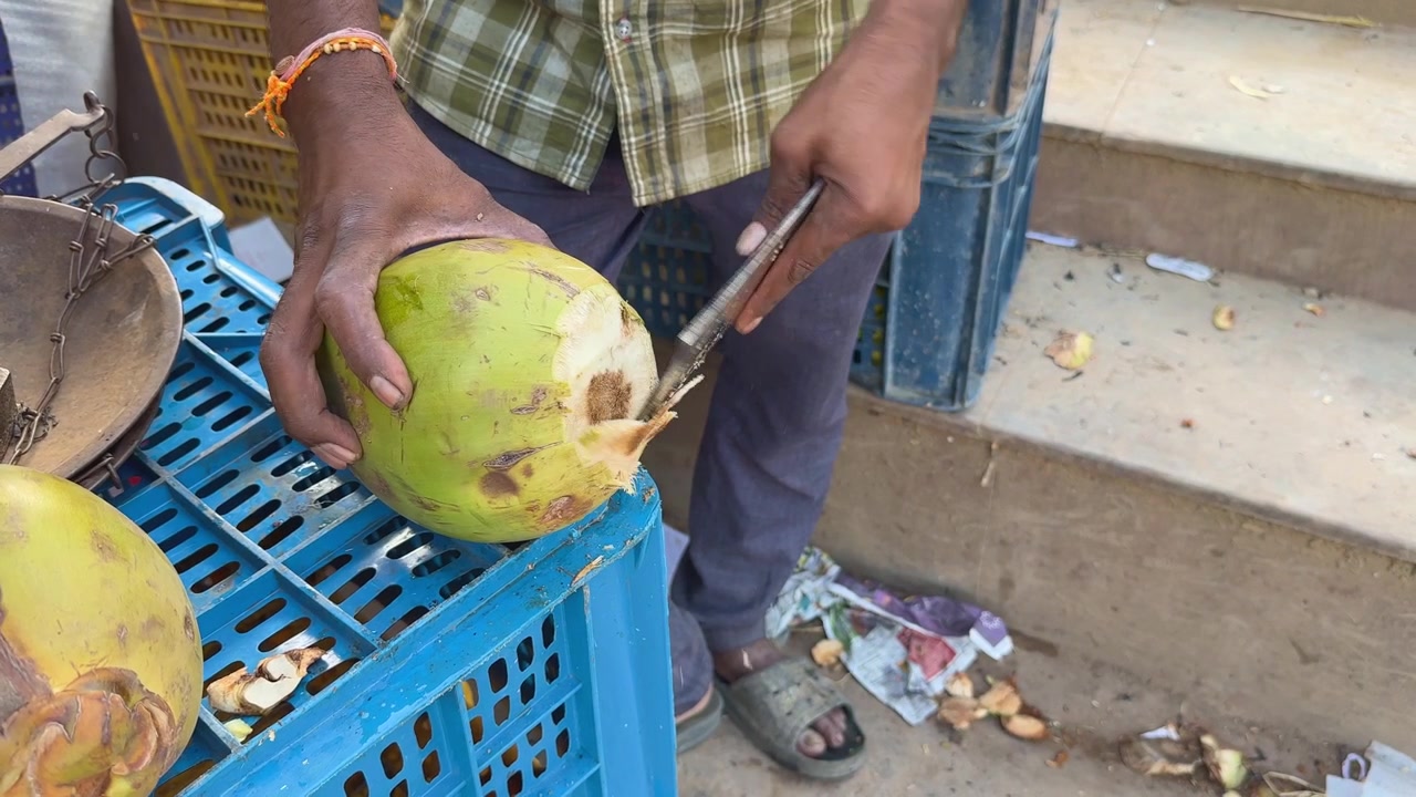 Primo piano di una mano che taglia una noce di cocco verde per acqua di cocco fresca.