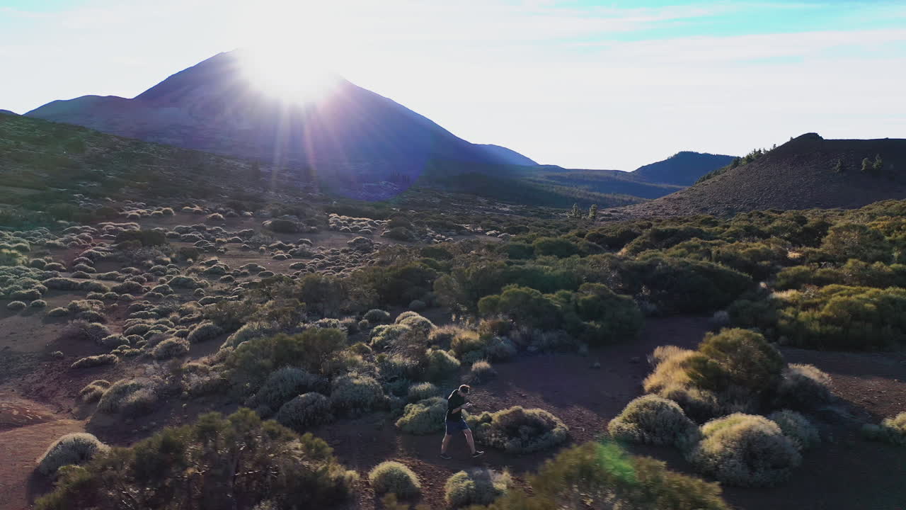Guy taking a drone shot around himself below mountain Teide,Spain,walking through bushes at sunset.