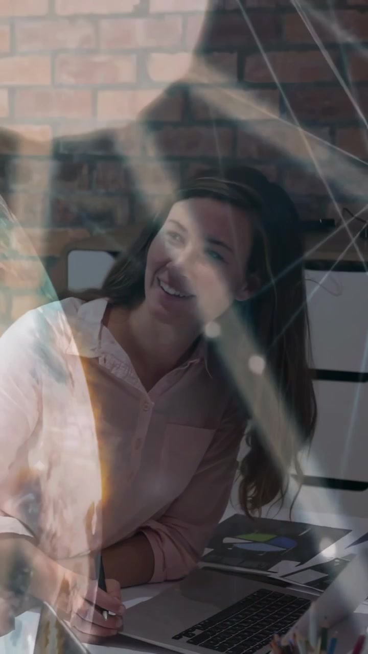 Video verticale: Donna che si avvicina al portatile per una revisione tecnica mentre un collega digita, con una sovrapposizione di un globo che oscura.