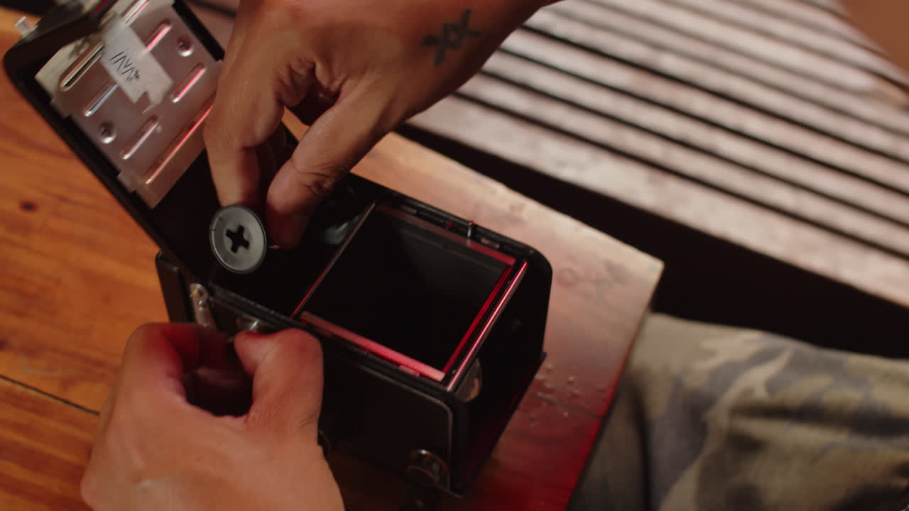 Male Hand Putting New Filmstrip into Analog Camera