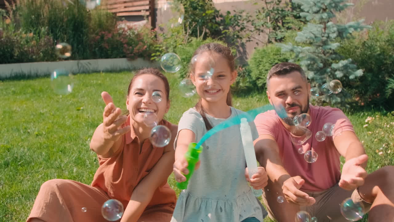 Cute Girl Making Soap Bubbles With Parents