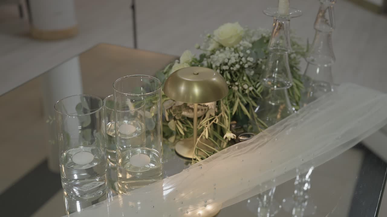 キャンドル、ガラスの花瓶、ゴールドのランプ、花で飾られた結婚式のテーブルのクローズアップ.