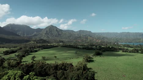 nubes esponjosas pasan a través de montañas tropicales sobre la bahía de hanalei y princeville, kauai, antena