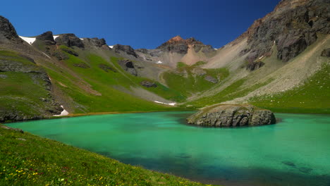 Aerial-cinematic-drone-Ice-Lake-Basin-Silverton-Island-Lake-aqua-blue-clear-water-alpine-tundra-stunning-mountain-range-wildflowers-mid-summer-daytime-blue-sky-beautiful-slow-pan-to-the-left-movement