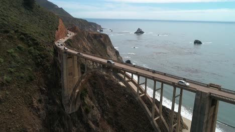 aerial drone stock video of cars passing on bixby bridge highway with water and shore below in big sur monterrey california