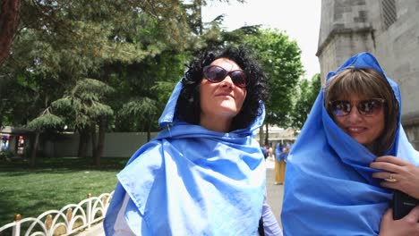 happy arab women wearing veil walk smiling at visit of blue mosque (sultan ahmed camii) in istanbul