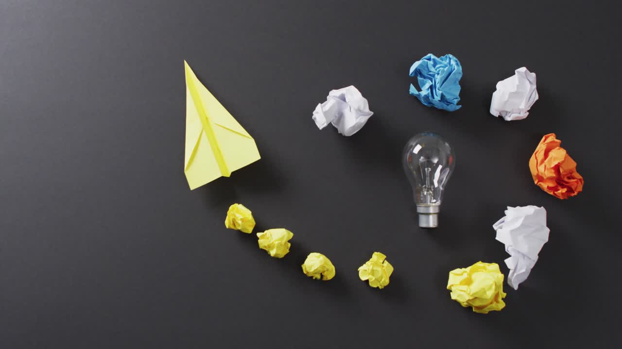 검은 바탕에 있는 다채로운 종이 공, 전구 및 비행기의 비디오