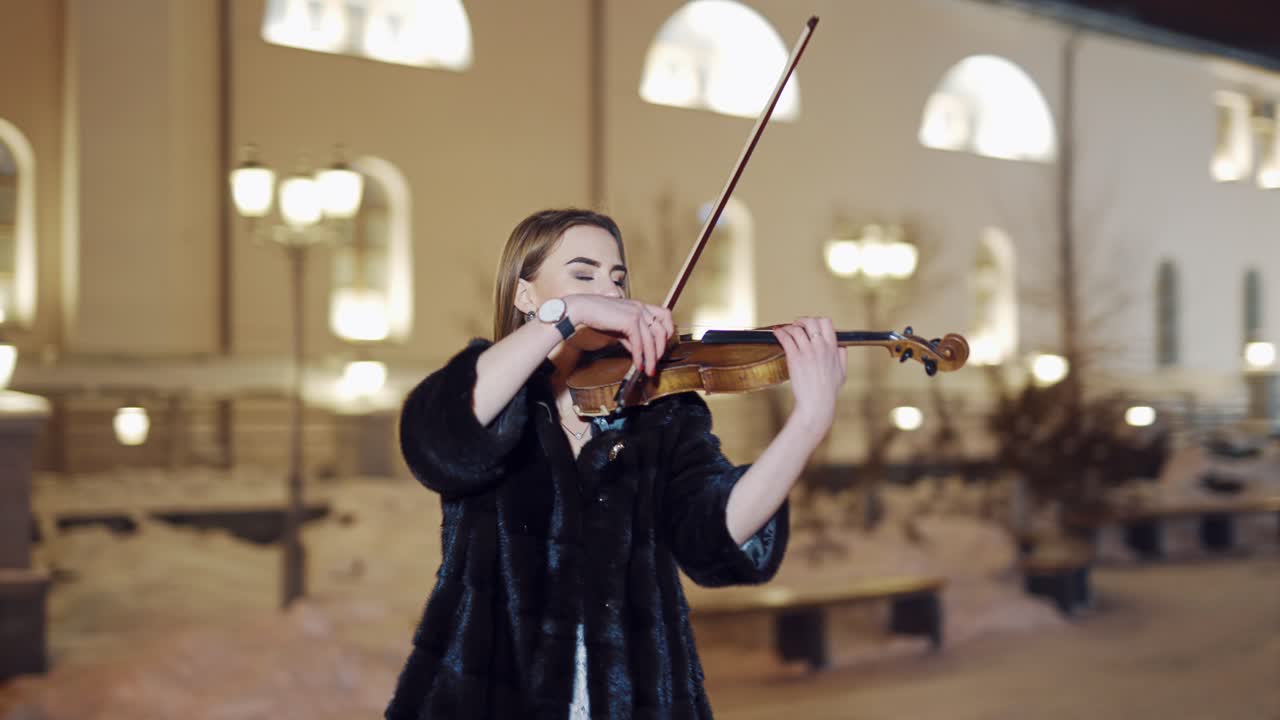 Woman playing on violin at nigh. Luxury girl playing on violin in winter environment