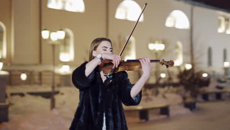 woman playing on violin at nigh. luxury girl playing on violin in winter environment