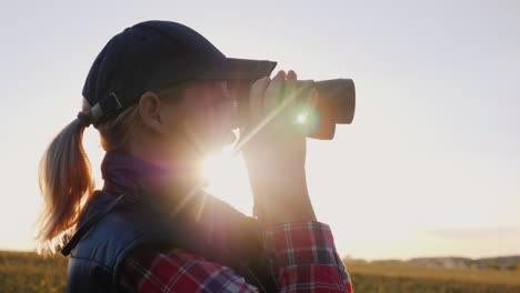 Eine-Frau,-Die-Durch-Ein-Fernglas-Bei-Sonnenuntergang-Reisen-Und-Safari-Konzept-4k-Video-Schaut