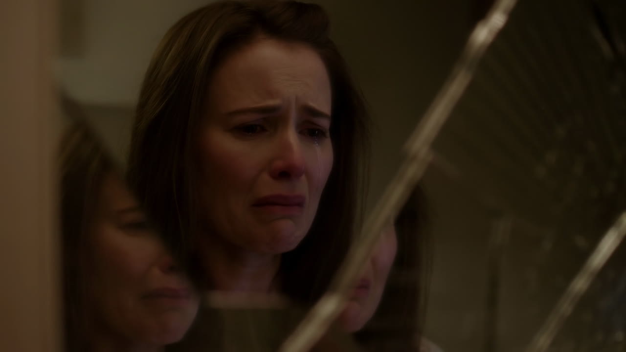 Donna triste che piange guardando il suo riflesso in uno specchio rotto