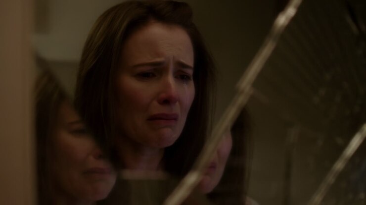 Donna triste che piange guardando il suo riflesso in uno specchio rotto
