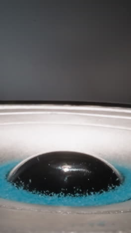 blue powder granules move lying near dust cap. loudspeaker dynamic diaphragm moves to produce sound. modern acoustic technology on blue background macro