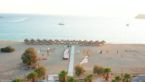 Aerial-shot-Milopotas-tropical-beach,-people-playing-volleyball-on-sand-at-Sunset,-Greece