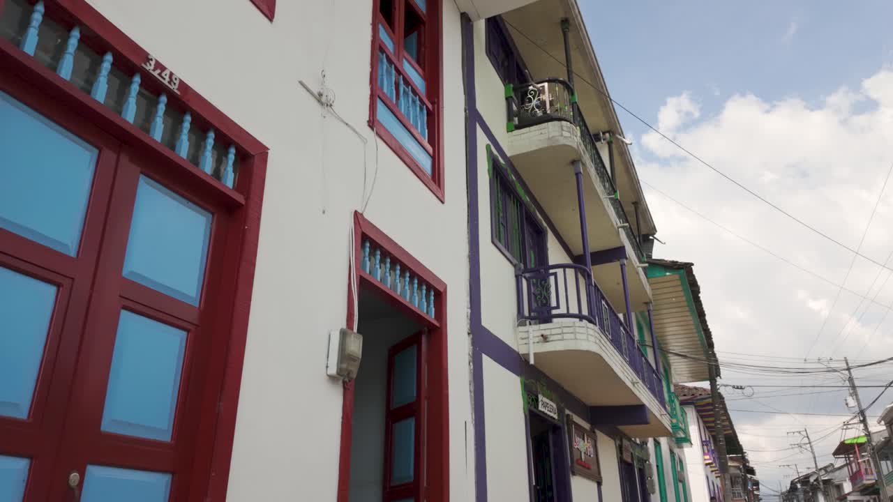 pov mirando hacia arriba caminando más allá de los balcones de madera de estilo colonial en filandia colombia