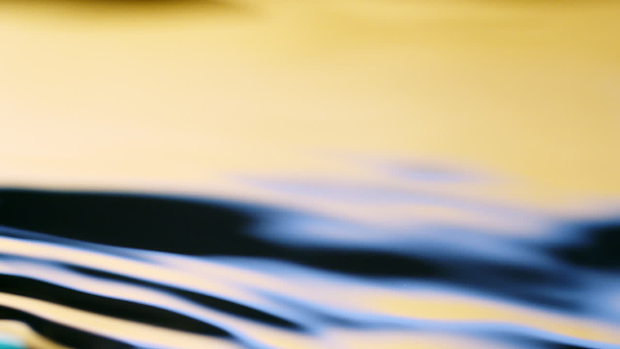 깨끗한 잔물결과 파동 굴절 배경을 가진 물 표면 노란색과 파란색 질감