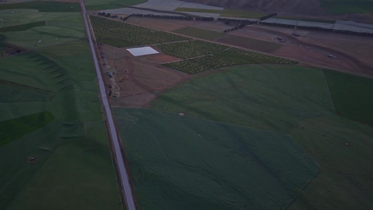 Aerial view gliding over vineyard fields and farmland near Cromwell at dusk