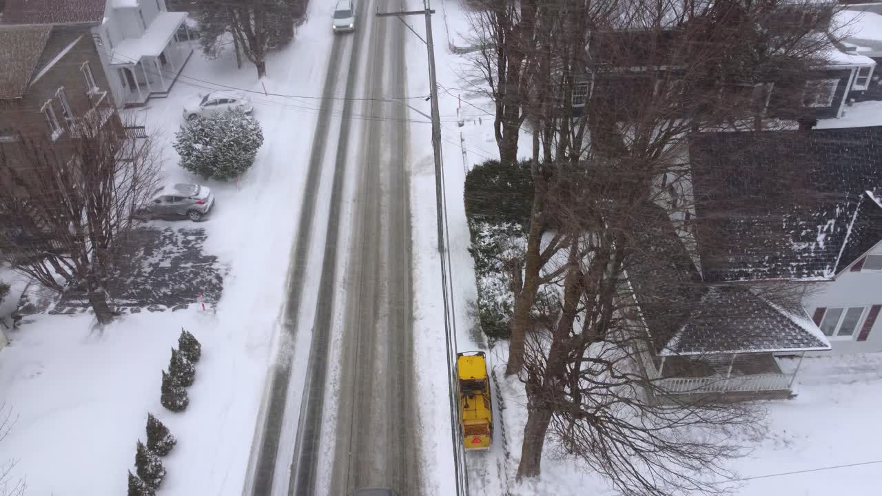 Typical snow-covered road with a single yellow snow removal vehicle, Orford, Quebec, Canada.