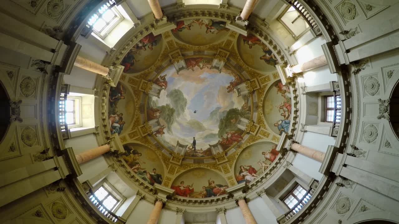 Telecamera rotante che rivela una cupola dipinta e un medaglione centrale in una rotonda, documentando un granello in movimento.