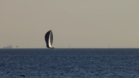 sailboat gliding across calm sea at sunset