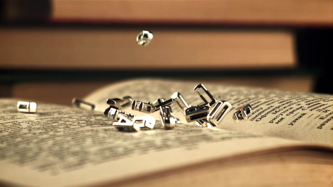 Lettere metalliche che cadono al rallentatore su un libro aperto