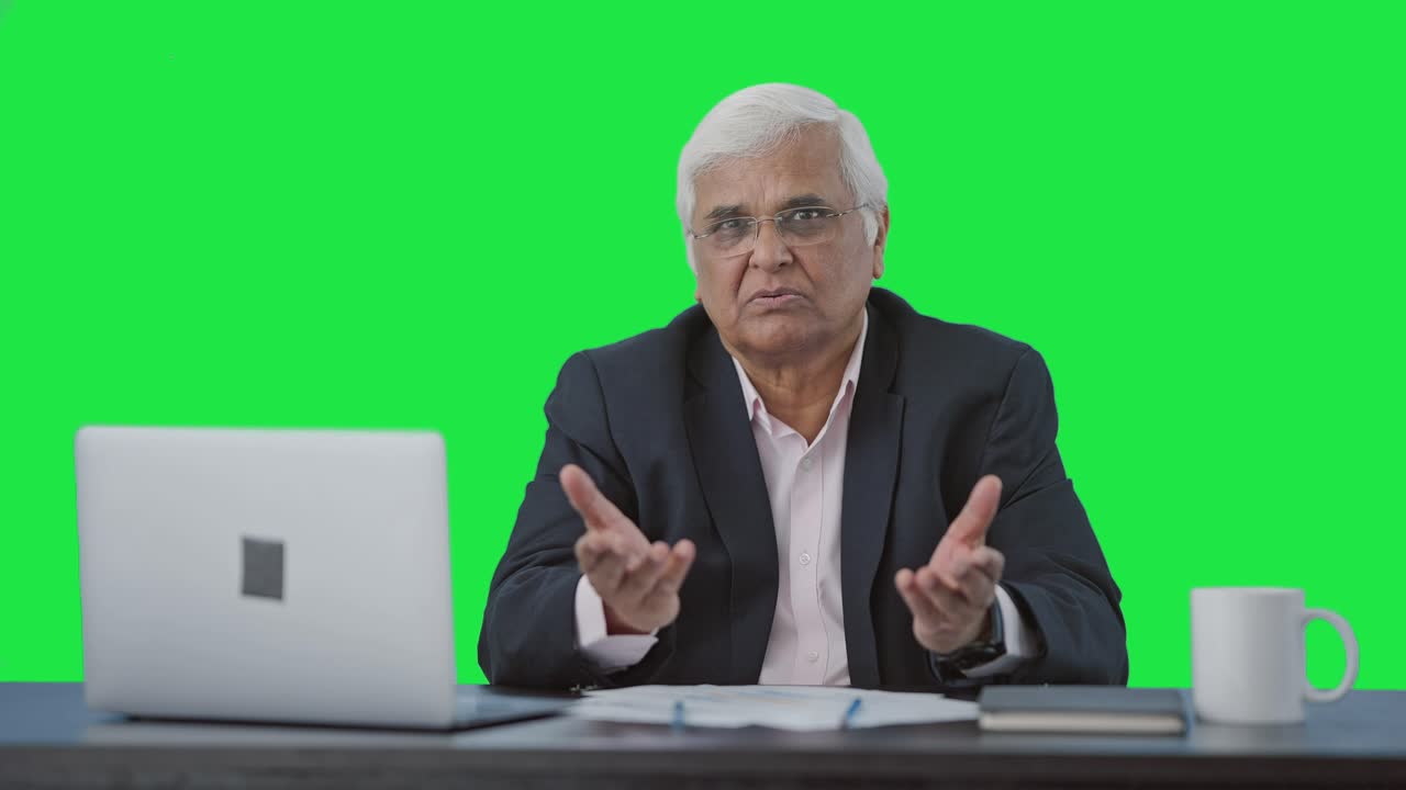 Serious senior Indian businessman talking to someone Green screen