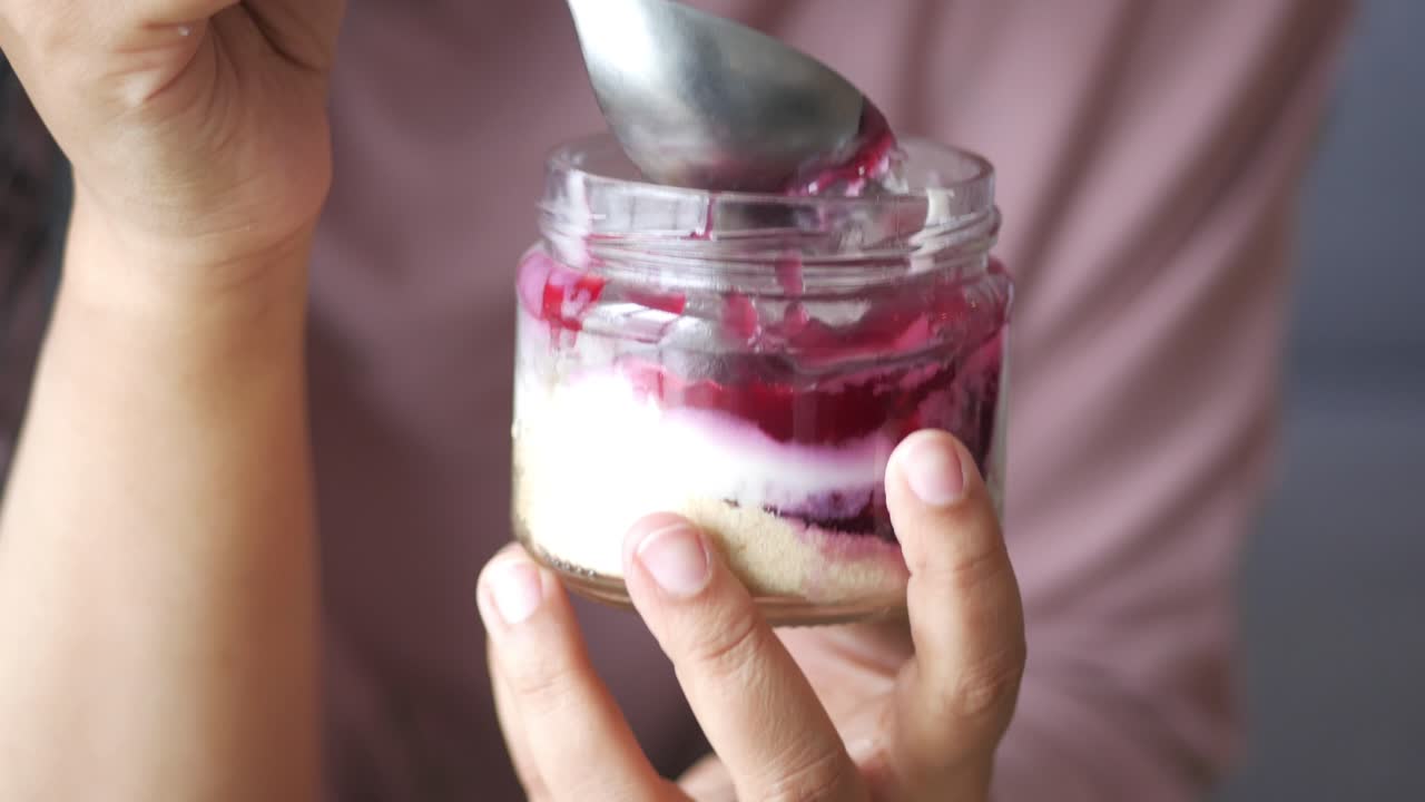 mujer comiendo un delicioso postre de pastel de queso de bayas de un frasco