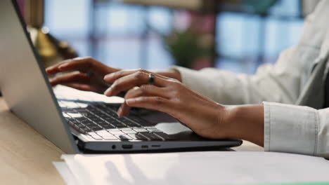 freelancer in home office typing on laptop keyboard, close up