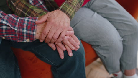 close up of caring elderly grandmother wife holding hands supporting senior grandfather husband