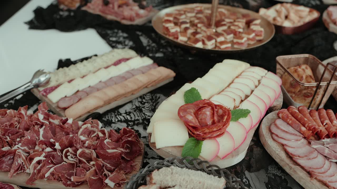 assorted cured meats and sliced cheeses served on wooden boards with mint and salami rose