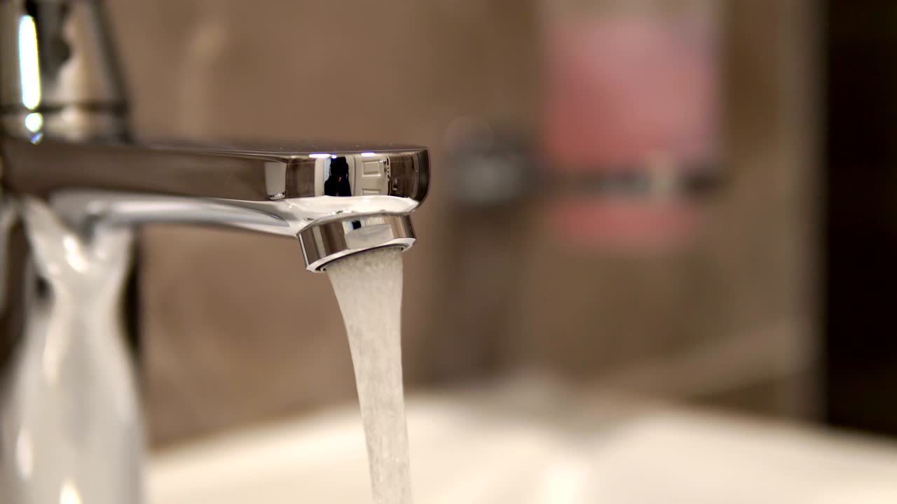 Metal tap water flowing, loop background, cinematic dof