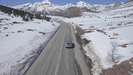 Conducción-De-Automóviles-En-Carretera-Rural-Con-Montañas-Durante-El-Invierno,-Seguimiento-Aéreo