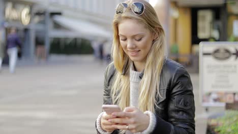 Lächelnde-Frau-Mit-Smartphone-Auf-Der-Straße