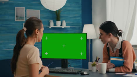 two women looking at computer with mock up green screen