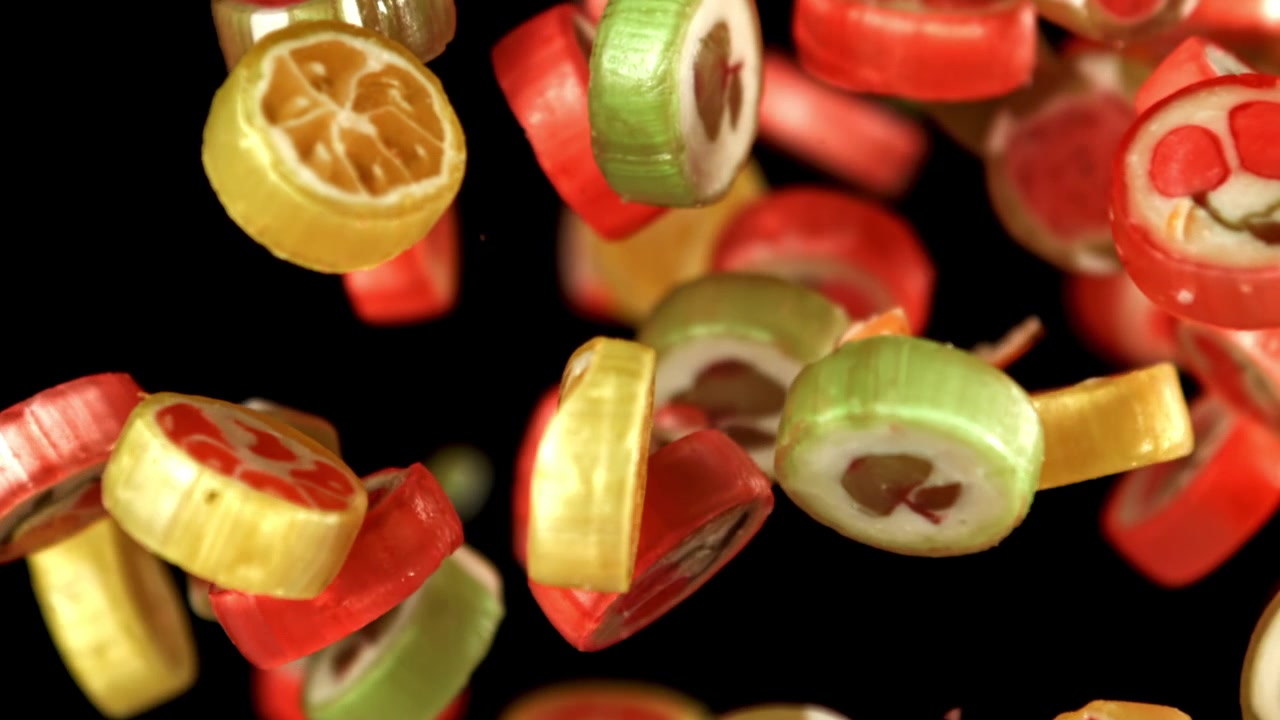 Eine Auswahl bunter Fruchtbonbons fällt in Zeitlupe