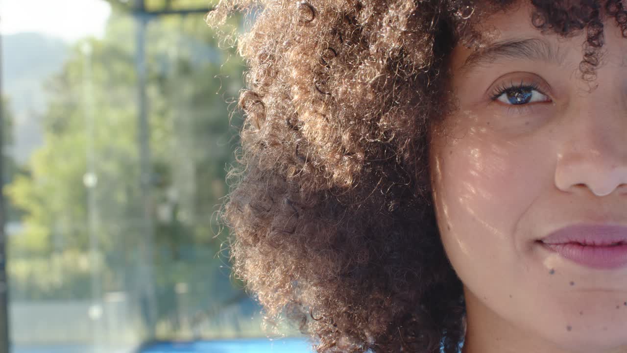 Donna afroamericana che si gode il sole, apre un occhio e sorride, con una collana blu, a bordo piscina, con spazio per il testo.