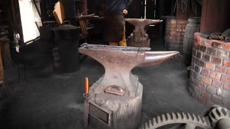 a blacksmith operates in a dimly lit forge, surrounded by tools and an anvil, creating an authentic historical atmosphere