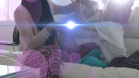 animación de puntos moviéndose sobre feliz medio oriente madre e hija divirtiéndose en el sofá
