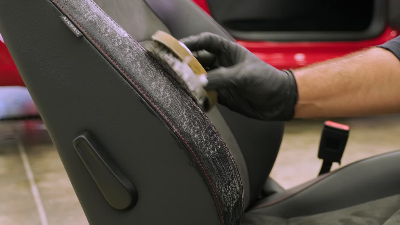 el especialista está involucrado en la limpieza en seco del asiento del coche eliminado. mecánico frotando espuma en la tela. etapa de limpieza a seco completa del coche. servicios de centro de detalles.