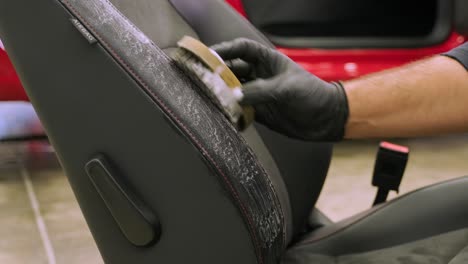 the specialist is engaged in dry cleaning of the removed car seat. mechanic rubbing foam into fabric. stage of complete dry cleaning of the car. detailing center services.