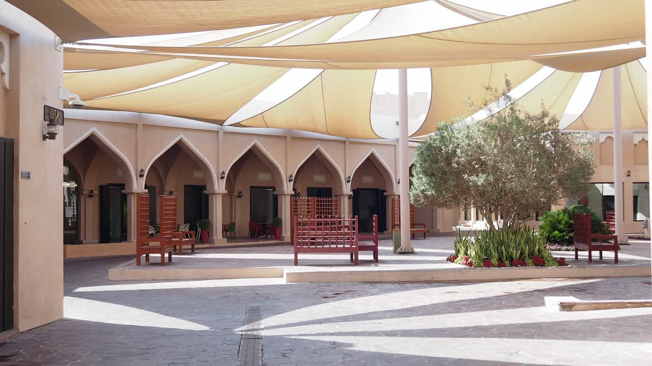 A serene courtyard with traditional architecture and a shaded area