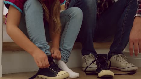 father helping her daughter to wear shoes on stairs in a comfortable home 4k