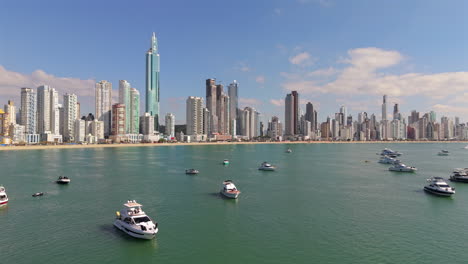 aerial drone shot capturing a group of luxury yachts anchored in the calm blue waters of balneário camboriú, brazil, with a striking background of high-rise buildings and clear skies