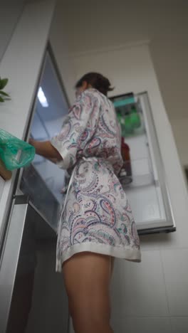 woman in pajama getting food from fridge