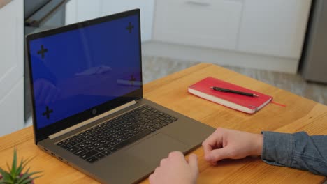 young businessman making video call on his laptop. blue screen.