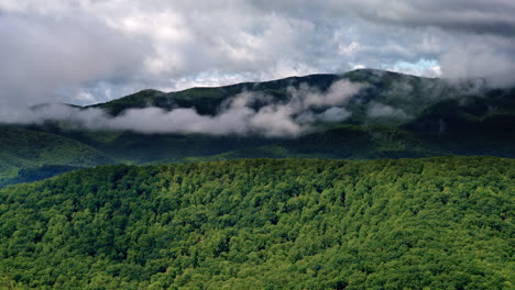 overhead cinematic shot of cloud systems pressing into misty mountain terrain