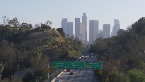 drone footage of downtown los angeles entrance with view of stadium way and dodger stadium overpass. the city skyline stands in the background under clear skies